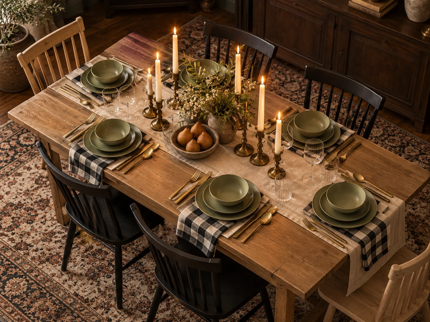 Elevated view of a candlelit timber dining table set for six with sage-green dishes, checked napkins and mixed black and natural-wood chairs. AI-generated editorial visualization; not exact retailer product photography.